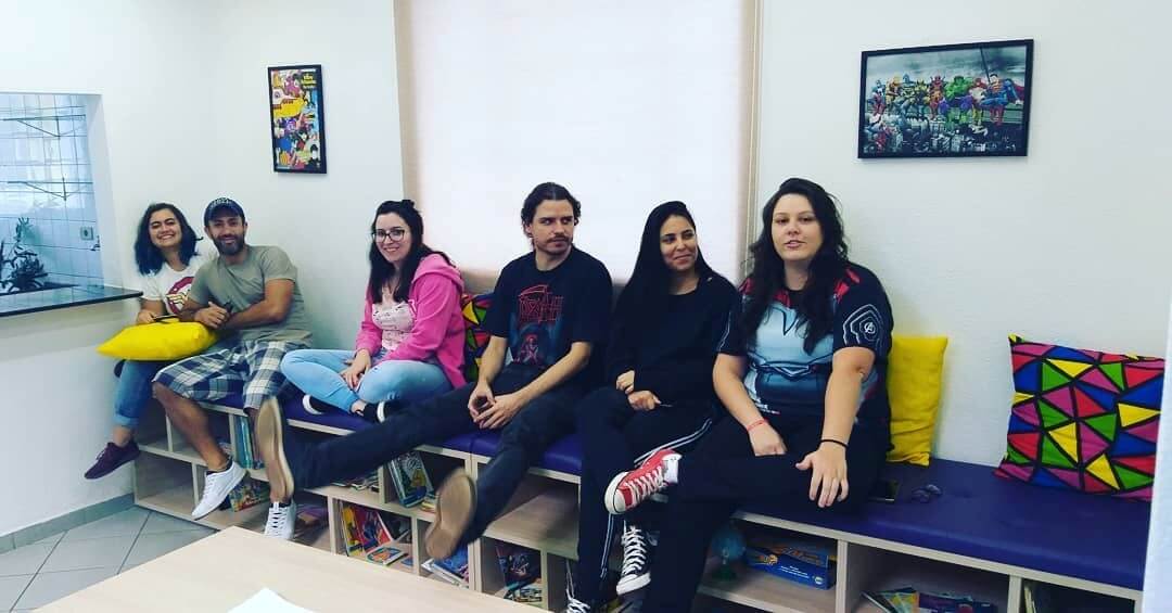 5 alunos adultos sentados junto ao professor de inglês